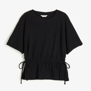 Svart topp  - Superfin svart T-shirt från hm med knyt på sidan. Säljer då den inte kommer till användning, helt oanvänd 