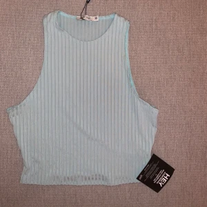 Ljusblå ribbad ärmlös topp från Hey You - Säljer en superfin ljusblå ribbad topp från Nelly. Toppen har en luftig och bekväm passform. Helt ny! 