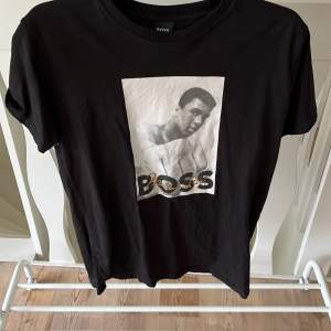 Säljer en svart t-shirt från Hugo Boss med Muhammed Ali tryck. Storlek L men sitter som M