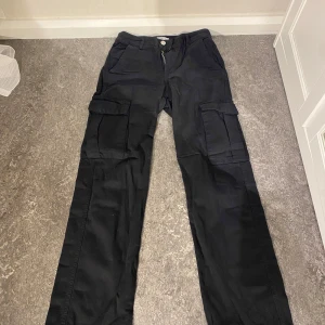 Svarta cargo byxor - PULL&BEAR - Väldigt fina cargobyxor som köpts från PULL&BEAR. Använda några gånger och har endast en defekt: snöret har öppnat sig vid foten av ena sidan av benet (se på bilden). Bortsett från det är de i relativt bra skick utan andra defekter🤍