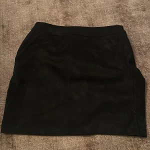 Kjol  - Svart kjol i mocka matriarl, dragkedja bak och fickor fram aldrig använd 