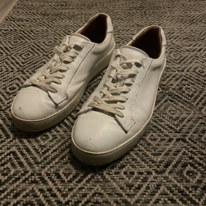 Vita sneakers med snörning - Säljer ett par vita sneakers i skinn med klassisk snörning. De är i välanvänt skick men fortfarande snygga och bekväma. Perfekta för vardagsbruk och passar till det mesta i garderoben.