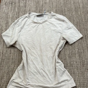 Vit t-shirt från Weekday - Säljer en enkel och stilren vit t-shirt från Weekday i storlek S. Perfekt basplagg för alla tillfällen. T-shirten är kortärmad och gjord i mjukt material för en bekväm passform.