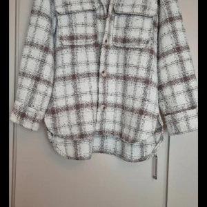 Rutig overshirt i beige och brun - Säljer en superfin rutig overshirt i beige och brun. Den har långa ärmar och knappar framtill. Perfekt för höst och vår, och den är i mycket bra skick. Passar både till vardags och lite mer uppklädda tillfällen. 🧥✨