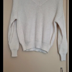 Vit stickad tröja från Amisu - Säljer en superfin vit stickad tröja från Amisu. Den har en v-ringad design och långa ärmar, perfekt för kyliga dagar. Tröjan är i bra skick och passar både till vardags och lite finare tillfällen. Perfekt att mysa i under höst och vinter!