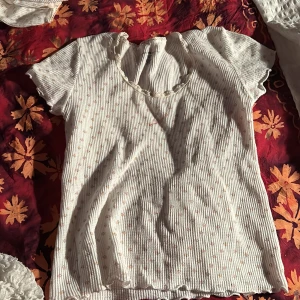 Vit ribbad topp med spetsdetaljer - Säljer en söt vit ribbad topp från Brandy Melville. Den har korta ärmar och fina spetsdetaljer vid halsringningen. Perfekt för sommardagar eller som ett lager under en kofta. Toppen är i bra skick och redo för nya äventyr! 🌼den har ett litet märke fast det fixas innan skickat!!!❤️❤️🫶