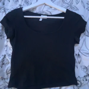 Svart kortärmad topp från H&M - Säljer en enkel och stilren svart topp från H&M, den är U-ringad och perfekt att ha till ex. Jeans eller mjukisbyxor, välanvänd men inga defekter tillsynes 