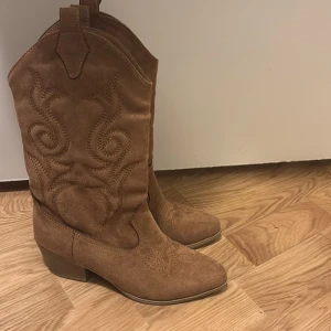 Bruna mocka cowboy boots - Snygga bruna cowboy boots i mocka med broderade detaljer. De har en låg klack och spetsig tå, perfekt för en stilren look. Passar både till vardags och festliga tillfällen. Skorna är i mycket bra skick och redo att användas direkt! Skorna är köpa i Istanbul. Aldrig använda. 