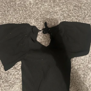 Svart ribbad topp från ONLY - Säljer en snygg svart ribbad topp från ONLY i storlek M. Toppen har korta ärmar och en söt knytning i ryggen. Perfekt för både vardag och fest! 🖤använd ett fåtal gånger och har ingen tecken på användning💕💕