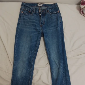 Blå jeansbyxor - Säljer ett par klassiska blå jeansbyxor i bra skick. De har en normal passform och är perfekta för vardagsbruk. Byxorna har en knappgylf och fem fickor, vilket ger dem en tidlös stil. Perfekta för både höst och vår!
