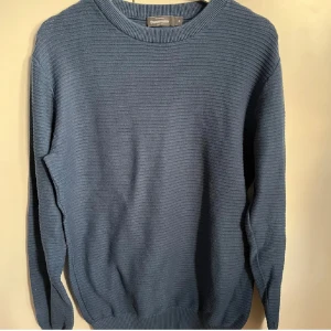 Blå stickad tröja från Dressmann - Säljer en snygg blå stickad tröja från Dressmann i storlek M. Perfekt för kyliga dagar med sin ribbade struktur och långa ärmar. Tröjan har en klassisk rund hals och är i mycket bra skick. Passar både till vardags och lite finare tillfällen. 🧶💙