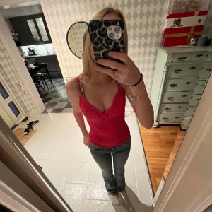 Neon pink spetslinne - Säljer ett snyggt rött linne med spetsdetaljer. Perfekt för sommaren eller en utekväll. Linnet har en tight passform och smala axelband. Det är både stilrent och bekvämt, och kan enkelt matchas med jeans eller kjol.