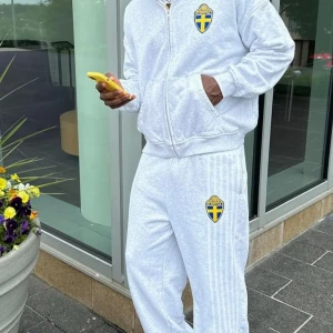 Grå hoodie med Sveriges landslagsemblem - Säljer en grå hoodie med dragkedja och Sveriges landslagsemblem på bröstet. Perfekt för sportiga tillfällen eller bara för att visa ditt stöd. Den är i bra skick och har en bekväm passform med långa ärmar och ribbade muddar.