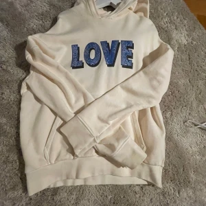 Beige/ Rosa hoodie från Zadig & Voltaire - Säljer en superfin beige hoodie från Zadig & Voltaire med texten 'LOVE' i blått på framsidan. Den är perfekt för en avslappnad stil och har en mysig luva. Passar perfekt till höst och vår! NYPRIS: 1200kr