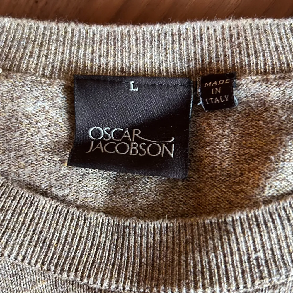 Säljer en stilren beige tröja från Oscar Jacobson i storlek L, men en passar nästan som en M. Tröjan har en klassisk design med ribbade kanter. Perfekt för både vardag och lite finare tillfällen. Passar bra till höst och vår!. Tröjor & Koftor.