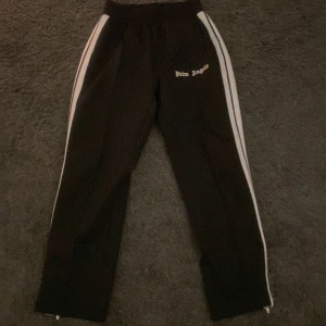 Palm angels - Hej säljer nu mina Palm angels byxor i storlek s perfekt nu till hösten dom är i fint skick men lite små fläckar på vita linjen som ni ser på andra bilden men det är inget man tänker på när man har de på sig passar både tjejer o killar