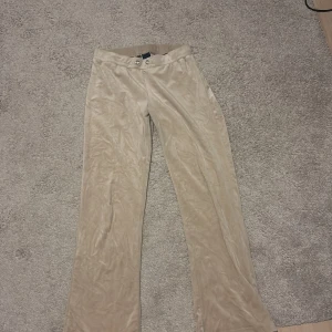 Beige byxor i sammet - Säljer ett par snygga beige byxor i sammet. De har en elegant och mjuk känsla, perfekt för både vardag och fest. Byxorna har en normal passform och stängs med knappar framtill. Perfekta för höst och vinter!