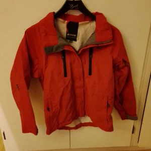 Jacka Från Didriksons - Röd jacka från didriksons i storlek 150. Gissar att den är till våren eller bara en vindjacka då den är tunn.  Katt finns I hemmet