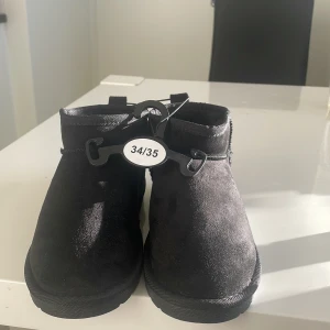 Svarta boots i mocka - Säljer ett par svarta uggs från lager 157, modell Teddy Lou/Ashoe. De är i storlek 34/35 och perfekta för höst och vinter. Aldrig använt då dom var för små eftersom jag inte testa i butik. Helt oanvänd och perfekt för att hålla fötterna varma och bekväma 