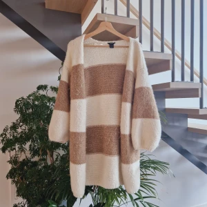 Randig kofta från Lindex - Mysig och stilren randig kofta från Lindex i beige och vit. Perfekt för kyliga dagar med sin stickade design och långa ärmar. Passar både till vardags och lite finare tillfällen. ✨