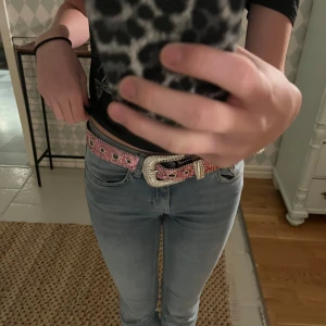 Rosa glittrigt bälte  - Säljer ett supercoolt rosa bälte med glittriga detaljer och strass. Bältet har en stor, dekorerad spänne som verkligen sticker ut. Perfekt för att ge lite extra bling till din outfit! Passar bra till både jeans och klänningar. 🩷✨