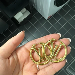 Guldiga örhängen  - Snygga och trendiga guldiga örhängen. Perfekta för att ge din outfit en lyxig touch. De är runda och har en glansig finish som verkligen fångar ljuset. Passar perfekt till både vardag och fest!