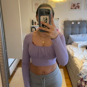 Lila ribbad topp - Säljer en superfin lila ribbad topp med långa ärmar. Den har en snygg croppad design och en smickrande passform som är perfekt för både vardag och fest. Toppen är i mycket bra skick och passar perfekt till jeans eller kjol. Perfekt för vår och sommar! Passar både Xs och S 