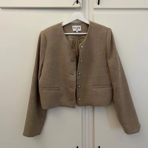 Beige kavaj från NA-KD - Säljer en stilren beige kavaj från NA-KD i mycket bra skick. Den har en klassisk design med rund hals och knappar framtill. Perfekt för både vardag och fest! Passar bra till höst och vår. Endast använd en gång! Nypris 699 kr 