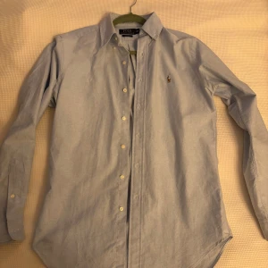 Oanvänd skjorta Ralph Lauren XS - Säljer en klassisk blå skjorta från Ralph Lauren i storlek XS. Skjortan har en broderad logga på bröstet och är helt oanvänd. 