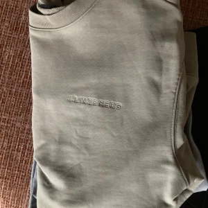 Beige tröja från J.Lindeberg - Säljer en stilren beige tröja från J.Lindeberg i storlek S. Tröjan är i mycket bra skick och har en diskret logga på bröstet. Perfekt för både vardag och lite finare tillfällen. Den är långärmad och gjord i ett mjukt material som känns skönt mot huden. Skick 9/10. Hör av er vid minsta fundering.