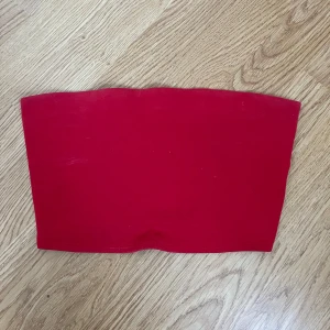 Röd tubtopp från H&M - Snygg röd tubtopp från H&M i ett stretchigt material. Perfekt för sommardagar eller en utekväll. Enkel och stilren design som passar till det mesta. Toppen är i bra skick och redo för nya äventyr!