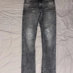 Grå jeans från Replay - Säljer ett par snygga grå jeans från Replay i nytt skick. De har en cool slitningseffekt och är gjorda av ekologisk bomull. Perfekta för en avslappnad stil med en modern touch. Passar till både vardag och fest!( ny pris 1800) priset är inte hugget i sten