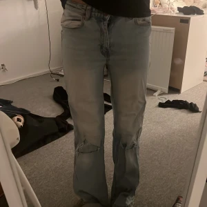 Ljusa slitna jeans - Säljer ett par ljusa jeans i baggy stil med hål på knäna. Dom är lite blekta av tvätten på bena men det syns knappt när dom sitter på. Storlek 160 och dom är från början ifrån lager 157. Det finns en liten fläck på insidan av ena benet men den är så pass liten att den knappt syns. Bra skick.
