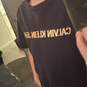 Säljer en snygg svart t-shirt från Calvin Klein Jeans i storlek S. Den har en klassisk design med märkesloggan i vitt och guld på bröstet. Perfekt för en casual look eller att styla upp med en kavaj. T-shirten är i mycket bra skick! 8,5/10