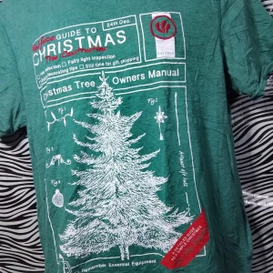 Grön jultröja med tryck - Säljer en grön t-shirt från Fatface med ett coolt jultryck. Den har ett stort vitt tryck av en julgran och text som 'Christmas Tree Owners Manual'. Perfekt för julfirandet eller som en rolig present! 🎄