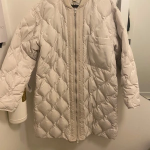 Beige dunjacka från H&M - Säljer en superfin beige dunjacka från H&M i storlek XS over sized. Jackan är quiltad med en dragkedja framtill och har en praktisk bröstficka. Perfekt för kyliga höst- och vinterdagar. Den är i mycket bra skick