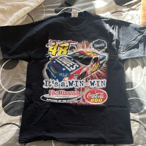 Svart NASCAR t-shirt med Jimmie Johnson motiv - Cool svart t-shirt med tryck av en NASCAR-bil och texten 'It's a WIN-WIN'. På baksidan finns en stor bild av Jimmie Johnson med texten 'Million Dollar Man'. Perfekt för racingfans! 🏎️