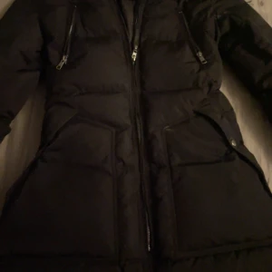 Svart dunjacka från ONLY - Säljer en svart dunjacka från ONLY i mycket bra skick. Jackan har en dragkedja framtill och två praktiska fickor med dragkedjor. Perfekt för kalla vinterdagar och håller dig varm och stilren. Pris kan diskuteras 