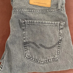 Grå jeans från Jack & Jones - Säljer ett par snygga grå jeans från Jack & Jones i storlek 29/30. De har en klassisk femficksdesign och är i mycket bra skick. Perfekta för både vardag och fest! 🖤