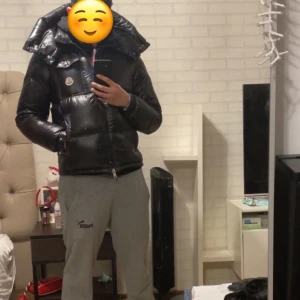 Svart dunjacka från Moncler - Säljer en snygg och varm svart dunjacka från Moncler. Jackan har en glansig finish och en hög krage som skyddar mot kyla. Perfekt för vintern och håller dig både stilren och varm. Passar bra till både vardag och festliga tillfällen. LUVAN  ÄR BORT TAPPAD‼️