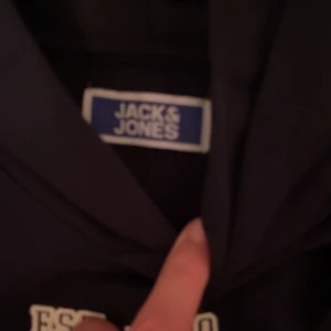 Mörkblå hoodie från Jack & Jones - Säljer en snygg mörkblå hoodie från Jack & Jones med tryck 'JCK & JNS' på framsidan. Perfekt för en avslappnad stil och passar bra till både jeans och joggers. Den har en klassisk passform och är superbekväm. Perfekt för höst och vinter!