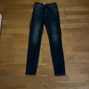 Mörkblå jeans från Nudie Jeans - Säljer mina helt nya jeans från nudie jeans. Jeansen är mörkblå och har en slim passform. De är för stora för mig och kommer då inte till någon använding. Den är helt ny och har inga defekter. Vid minsta lilla fundering är det bara att höra av.