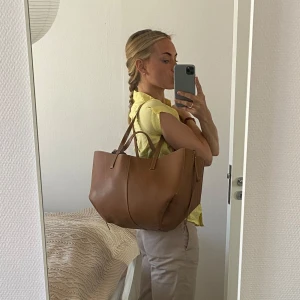 Polene Cyme Bag (Camel) - Brun axelväska i skinn - Säljer min fina väska från Polene som jag köpte i våras (kvitto finns), för att jag inte fått så mycket användning för den. Det är rymlig och går att ha både invikt och helt utfälld, man får plats med massa grejer, perfekt skolväska eller jobbväska! Dustbagen har jag kvar och skickar självklart med! Skriv för fler bilder! Skicket är jättebra, den är i princip ny