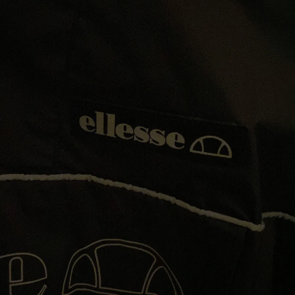 Säljer en svart vindjacka från Ellesse i storlek 152-158. Jackan har en halv dragkedja framtill och en stor ficka med Ellesse-logga på bröstet. Perfekt för blåsiga dagar och har en sportig look. Använd ett fåtal gånger, så den är i mycket bra skick.. Jackor.