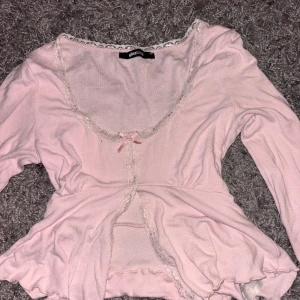 Rosa topp från Gina Tricot - Originalpris 299:- - Söt rosa topp från Gina Tricot med spetsdetaljer och en liten rosett framtill. Toppen har långa ärmar och en v-ringad design. Originalpris 299kr