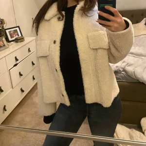 Beige teddyjacka från Zara - Säljer en supermysig beige teddyjacka från Zara i storlek L men sitter som M . Jackan har långa ärmar och knappar framtill, samt två stora fickor på bröstet. Perfekt för höst och vinter när du vill hålla dig varm och stilren.  