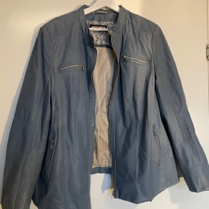 Blå skinnjacka Gerry Weber  - Säljer en snygg blå skinnjacka från Gerry Weber i bra skick. Jackan har en stilren design med dragkedjor på bröstet och sidorna. Perfekt för både höst och vår! 