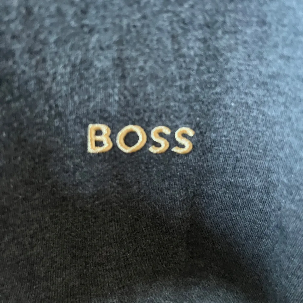 En mörkgrå zip hoodie från boss, med guldigt BOSS märke på vänster bröst. Väldigt bra skick, använd några fåtal gånger. Storlek M. Hoodies.