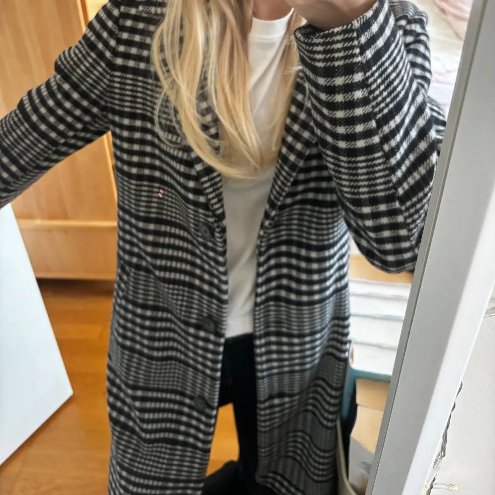 Säljer en snygg svartvit rutig kappa i mycket bra skick. Den har en klassisk långärmad design och är perfekt för höst och vår. Kappan har en normal passform och passar till alla tillfällen. Passar de som är s/m. Takit.