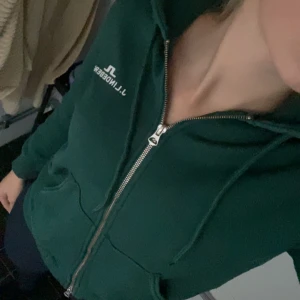 Grön hoodie med dragkedja från J.Lindeberg - Säljer en snygg grön hoodie från J.Lindeberg. Den har en dragkedja framtill och är perfekt för en avslappnad stil. Hoodien passar till tröning och vardags. Är i nyskick och kostar ordinarie 1500, mitt pris 600